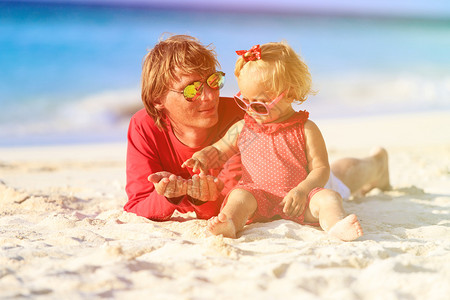 父亲和可爱的小女儿在沙滩上玩沙图片