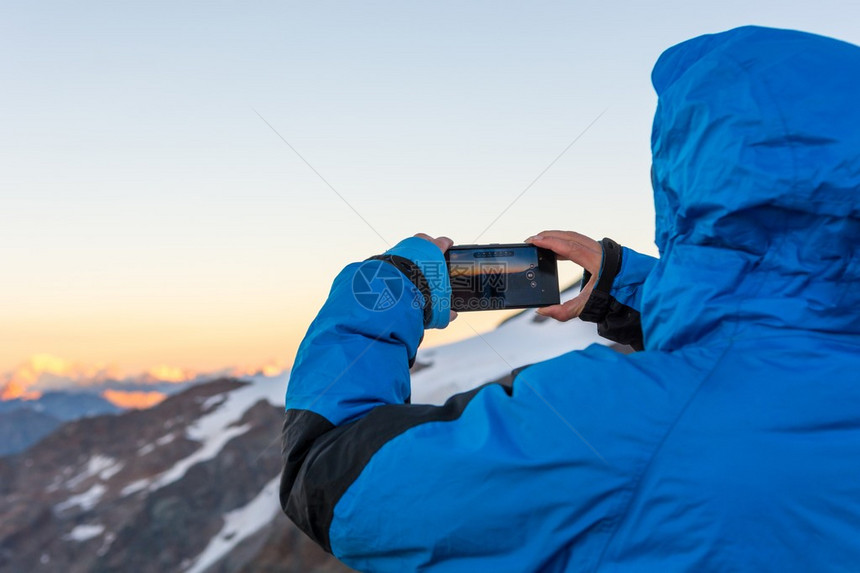 女人在日出时为勃朗峰拍山照图片