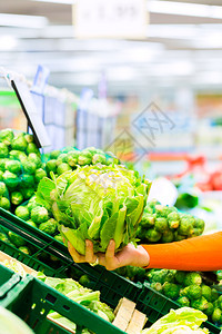 在超市购物时买花椰菜的女人审查高清图片素材