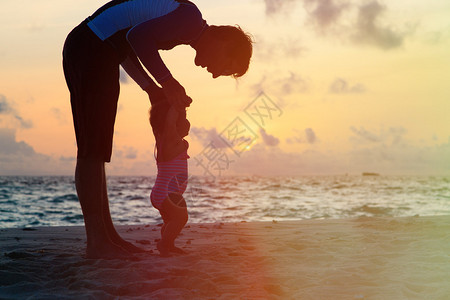 父亲和小女儿在日落海滩图片