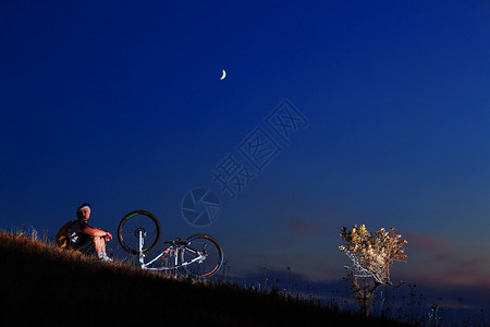 在午夜背景下修车的骑自行车者图片