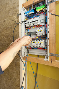 电工在电气开关柜上用螺丝刀的手图片