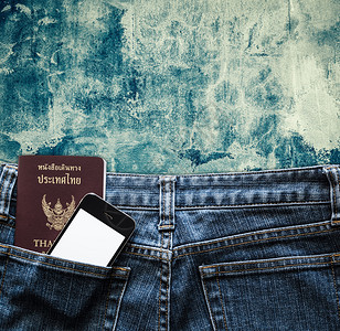 蓝色牛仔裤手机和护照放在旧背景口袋图片