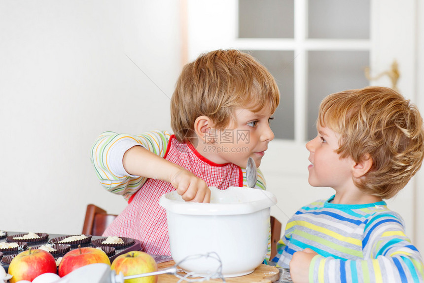 两个小兄弟姐妹在家用厨房里烤苹果蛋糕男孩子与搅拌机鸡蛋和水果一起工图片