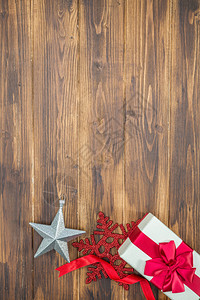 白色礼物红色丝绸包裹与雪花和木制背景上的星形图片