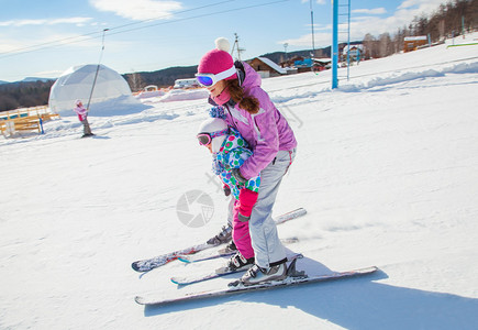 女教练在冬季度假胜地教孩子滑雪图片