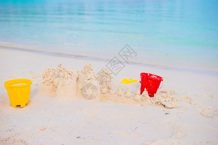 白沙滩上的沙堡有塑料小孩的玩具图片