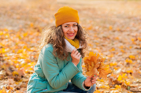 有秋叶的年轻姑娘手握着秋叶落下黄色的橄图片