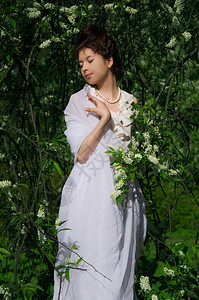 长着野樱桃开花树枝的东方女人和穿长白裙图片