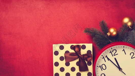 巨大的时钟和礼物圣诞节树枝红背景图片