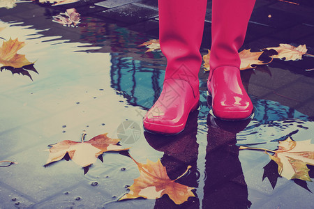 有粉红色雨靴的女人在雨季秋天图片