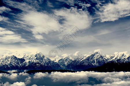 蓝色连绵起伏的云彩和雪山峰顶景观图片
