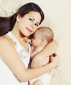 肖像快乐年轻的妈妈和宝宝在家里的床上睡觉t图片