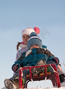 两个孩子在雪地里拉着雪橇滑行图片