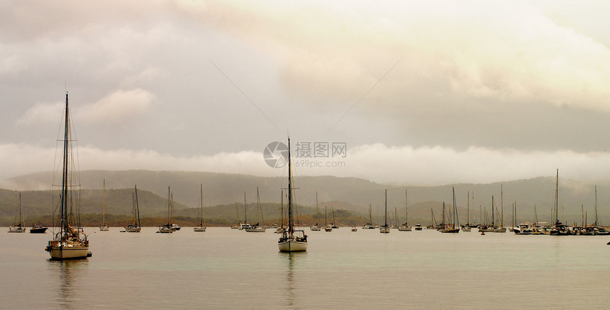 巴利阿里群岛Menorca海岸附近BalearicIsland岛边有小游艇停在云中和雨天的海景图片