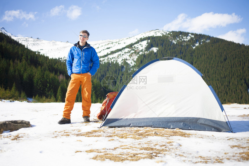 一名游客站在一个帐篷和山地背图片