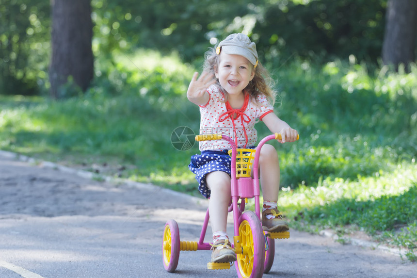两岁的笑女孩戴着灯芯绒平帽和圆点服装骑自行车的孩子粉色图片