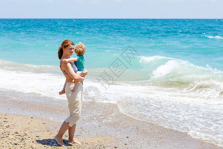年轻母亲和小男孩在海边玩得开心图片