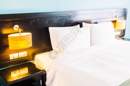床上的白枕头和室内卧室壁装饰上灯具上的白枕头图片
