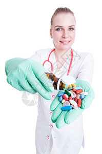 带着手套手里拿着一罐药丸和胶囊的美丽的笑着微笑的医生图片