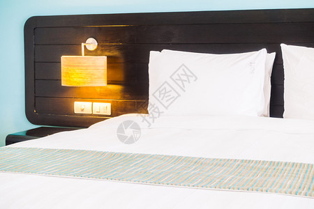 床上漂亮的豪华白色枕头和卧室内墙壁装饰上的灯图片