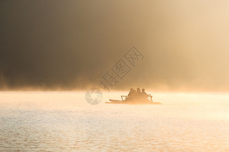 人们在日出时在湖上进行竹筏漂流图片