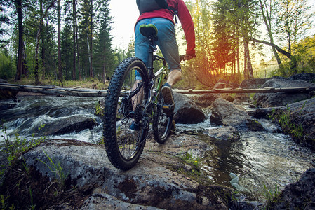 日落时骑着自行车骑在河边的石头上图片