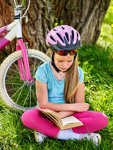 骑自行车的女孩女孩骑自行车骑自行车的女孩坐在自行车附近的绿草上图片