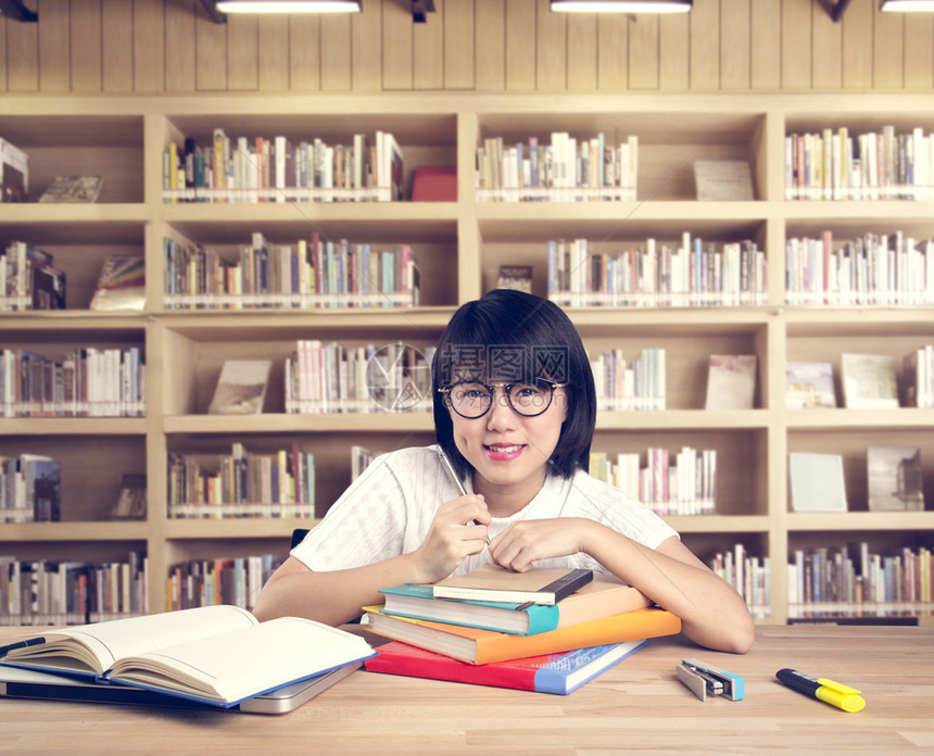 聪明的亚洲学生肖像在图书馆图片