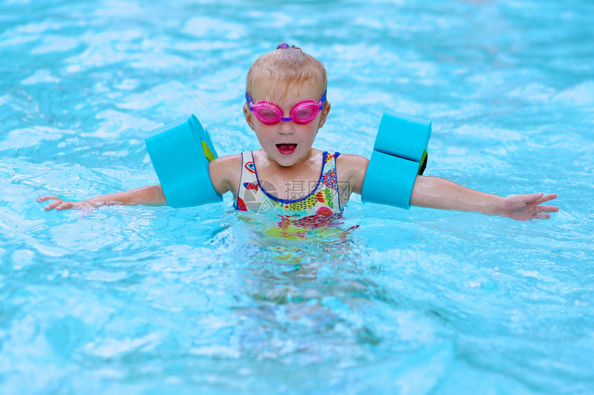 小孩享受游泳池可爱的蹒跚学步的女孩穿着五颜六色的泳衣粉红色的护目镜和蓝色的臂章在水中玩乐可爱的运动员孩子提倡健图片