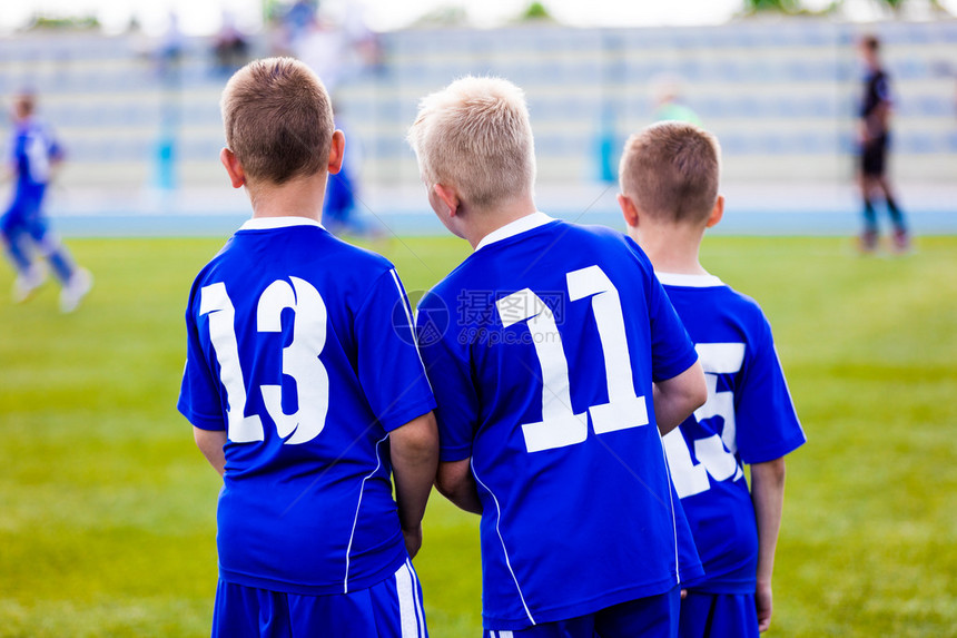 年轻的足球队预备队球员站在一起观看青年队的足球锦标赛比图片