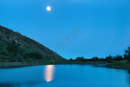 景观与湖上方的月亮深蓝夜和月光反射在水中图片