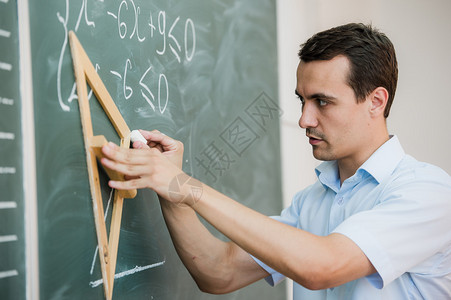 年轻的教师或学生在黑板上画三角背景图片