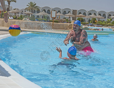 父亲和儿子在度假时在热带旅馆度假胜地游泳池图片
