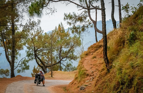 妇女将自行车推上山坡在尼泊尔一条通往达曼图片