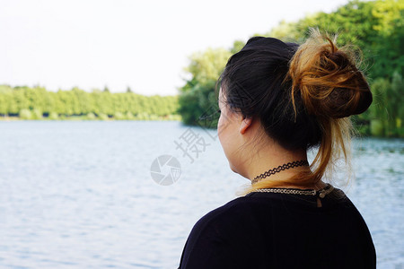 看湖的年轻女子的背影或后视图图片