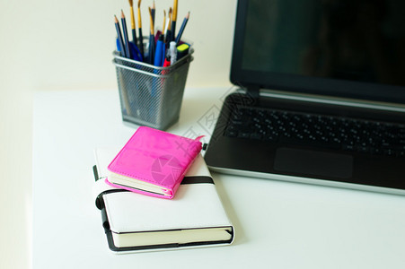 白色办公桌上的两本粉色和白色笔记本办公文具和黑图片