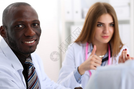 年轻英俊的黑人男医生与在后台工作的同事的画像背景图片