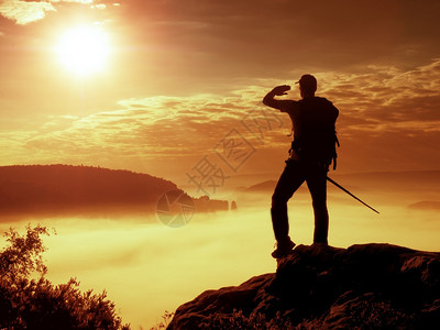 高大的游客手里拿着杆子在落基山脉的雾蒙的早晨背着大背包的徒步旅行者站在迷雾笼罩的山谷上方背景图片
