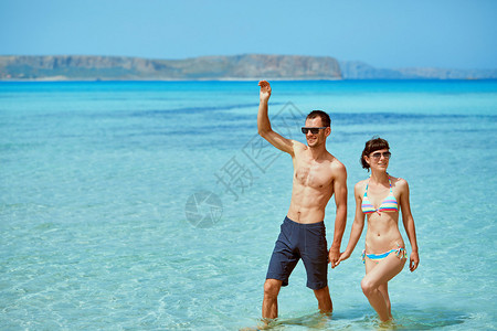 的年轻幸福的情侣在阳光明媚的日子在沙滩上散步图片