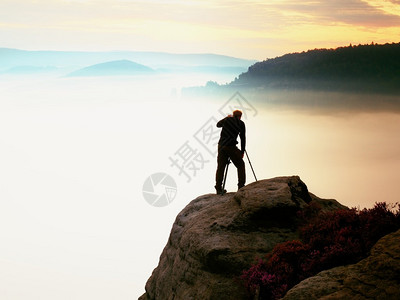 专业摄影师用相机和三脚架在岩石峰上拍照图片