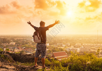 剪影男子背包客站举起成功在山顶上的成就在日落图片