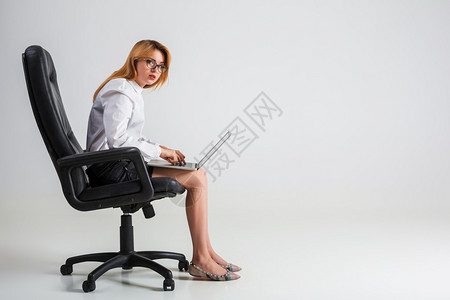 坐在椅子上并使用笔记本电脑的年轻女青年在艰苦工作的压力下背景图片