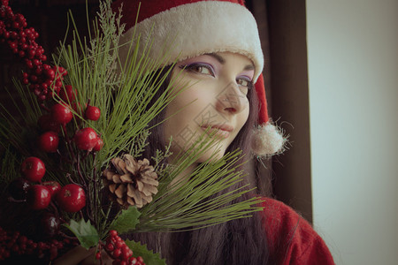 穿圣诞老人衣服的漂亮女孩手拿着圣诞树枝装背景图片