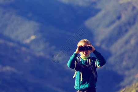 小男孩带着双筒望远镜在山上远图片