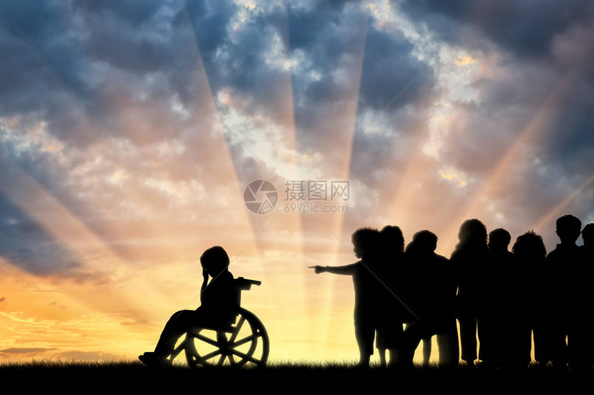 坐在轮椅上哭泣的残疾孩子和孩子们在日落时追着他图片