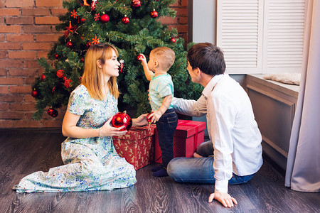 小男孩装饰圣诞树玩具假期礼物和新年概念图片