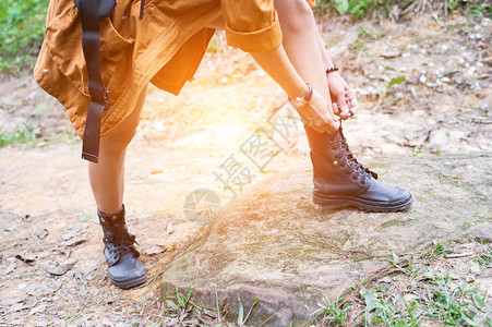 在森林小径上系鞋带的女人徒步旅行图片