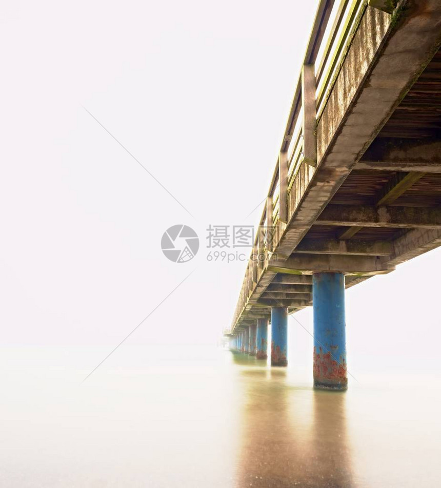 游客在泥海之上的码头雨雾般的天气和光滑的水图片