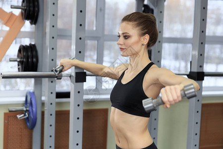 美丽的健身女人举哑铃举重的运动型女人适合锻炼肌肉的女孩图片